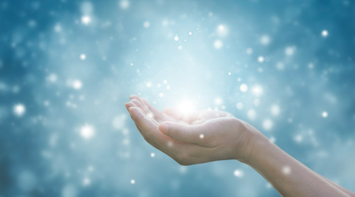 A cupped pair of hands palms facing upward that appears to be holding sparkling dots of light